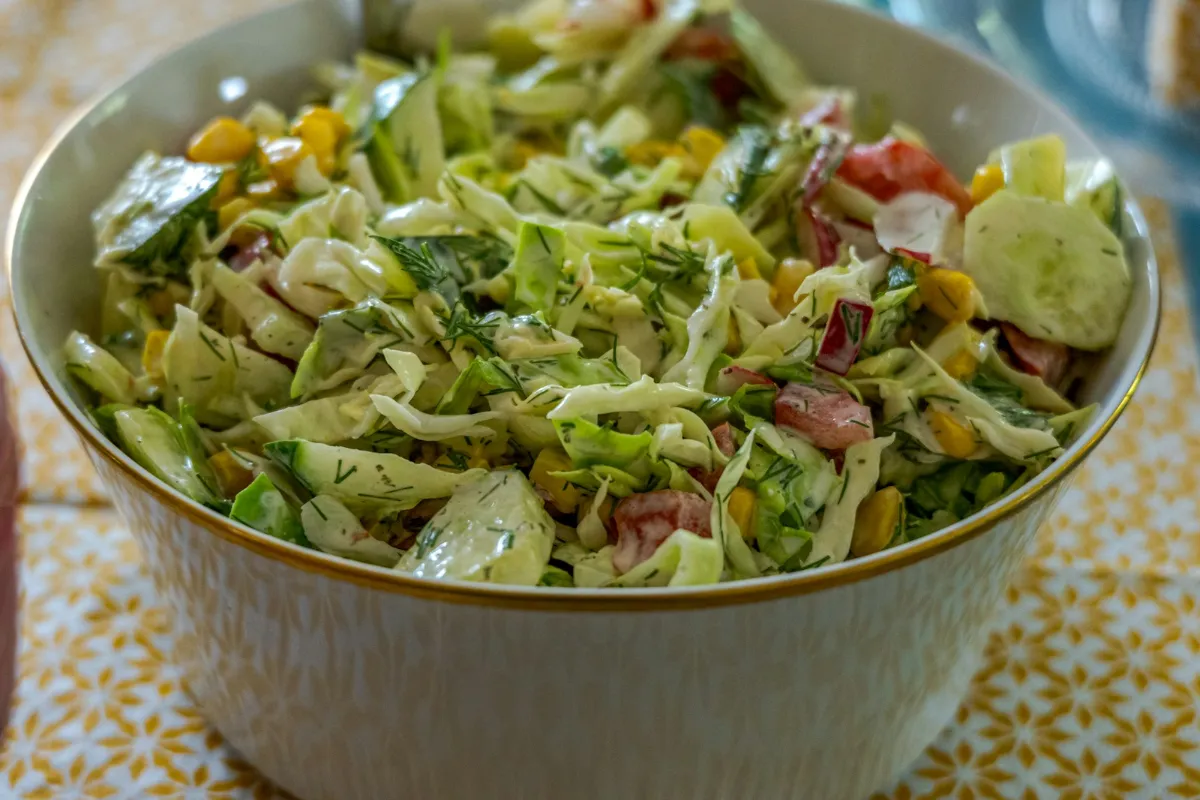 A bowl of fresh cabbage salad with sweetcorn and cucumber