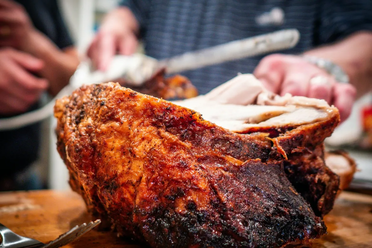 A large roast pork joint being carved on a wooden board