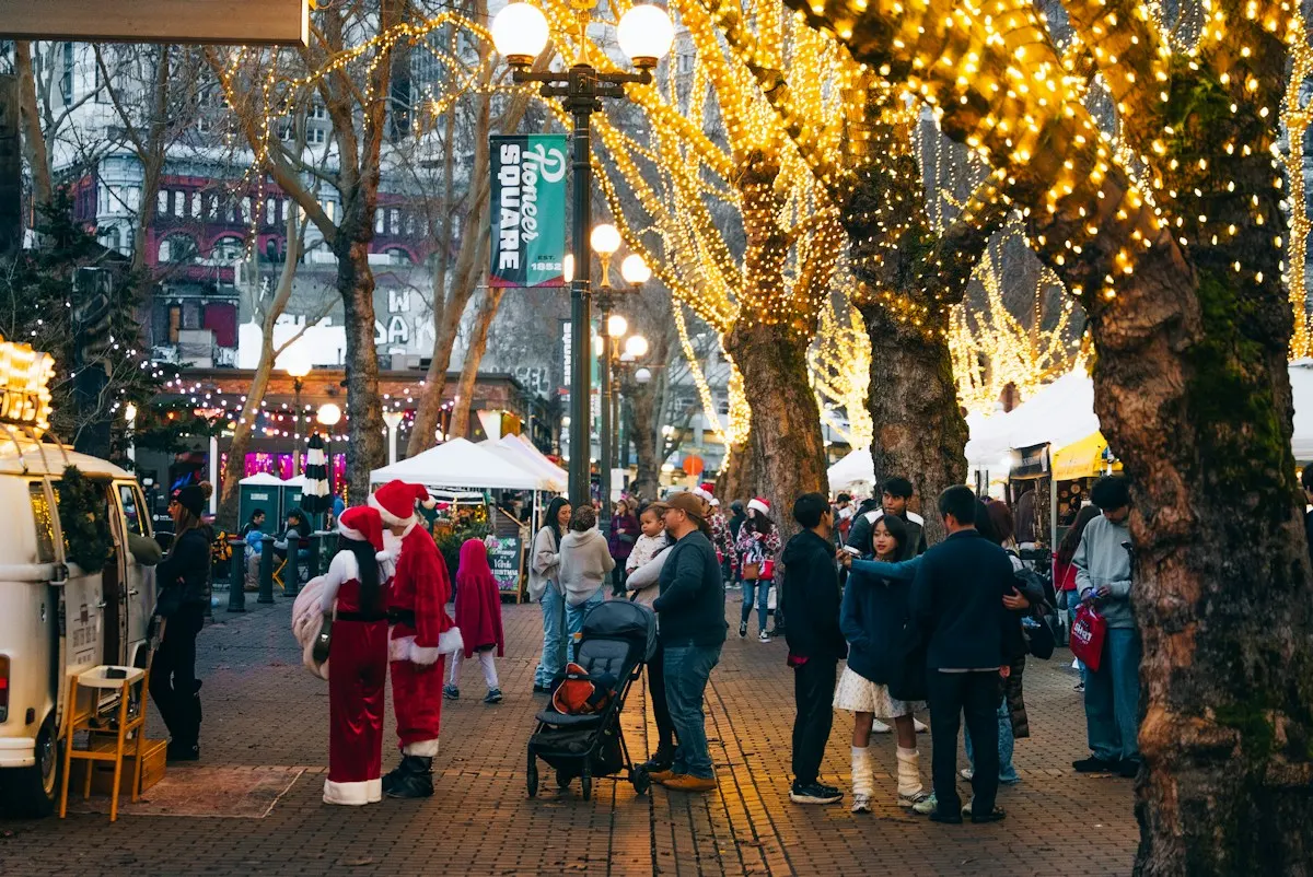 A street lit with fairy lights in the trees at a festive market